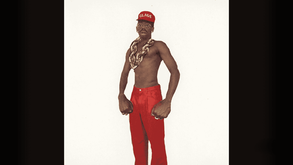 Tyler, the Creator in big necklace chain, and red hat and pants.